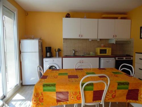 une cuisine avec une table avec des chaises et un réfrigérateur dans l'établissement Appartement T2 calme avec terrasse et parking - 400m de la plage - FR-1-750-85, à Canet
