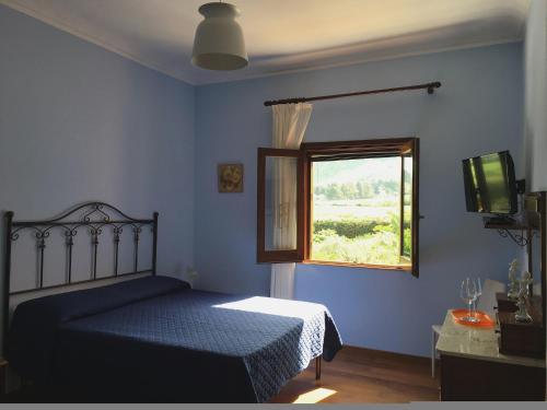 a blue bedroom with a bed and a window at Baglio Buccellato in Scopello