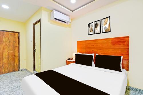 a bedroom with a white bed with a wooden headboard at Super Hotel O Madlen in Hyderabad
