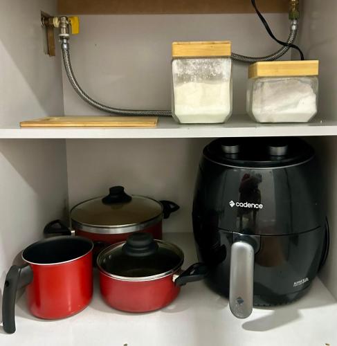 a coffee maker and pots and pans on a shelf at Apartamento aconchegante e moderno com varanda na Rua Guaicurus in Sao Paulo