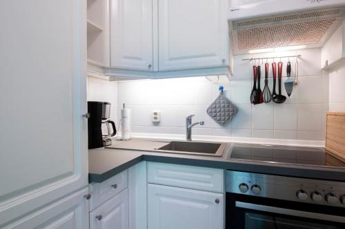 a kitchen with white cabinets and a sink at Haus Meeresgruß Ostseebrise in Grömitz