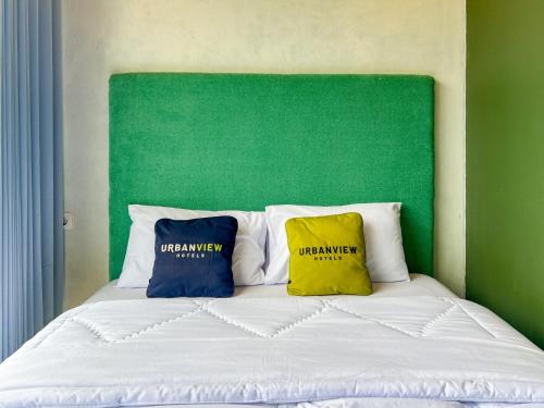 two pillows on a bed with a green headboard at Urbanview Hotels Asmaraloka Umbrella in Kejajar