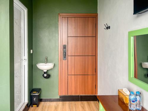 a bathroom with a wooden door and a sink at Urbanview Hotels Asmaraloka Umbrella in Kejajar