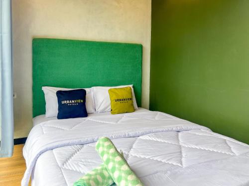 a bed with two pillows and a green wall at Urbanview Hotels Asmaraloka Umbrella in Kejajar