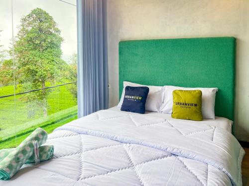 a bedroom with a bed with two pillows and a window at Urbanview Hotels Asmaraloka Umbrella in Kejajar