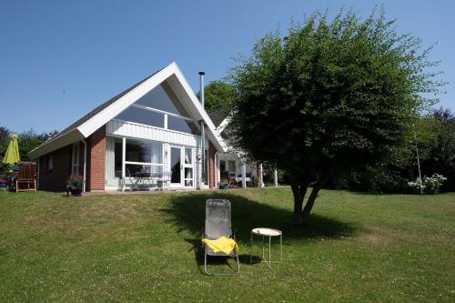 a chair sitting in the grass in front of a house at Twinhus Süssau in Süssau
