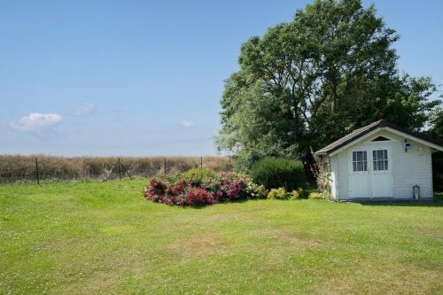 a small white shed in a field with flowers at Twinhus Süssau in Süssau