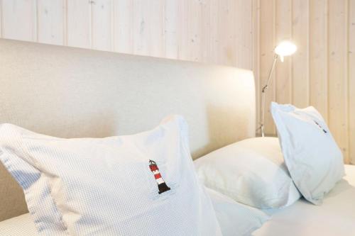 a bed with white pillows and a lighthouse pillow at Twinhus Süssau in Süssau