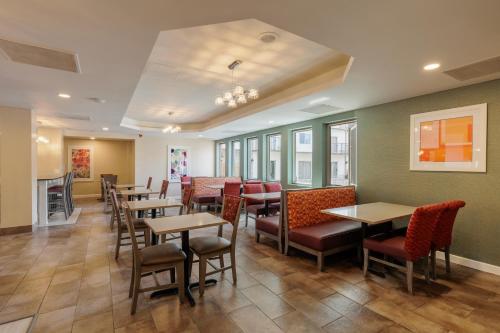 a restaurant with tables and chairs in a room at Orangewood Inn & Suites Kansas City Airport in Kansas City
