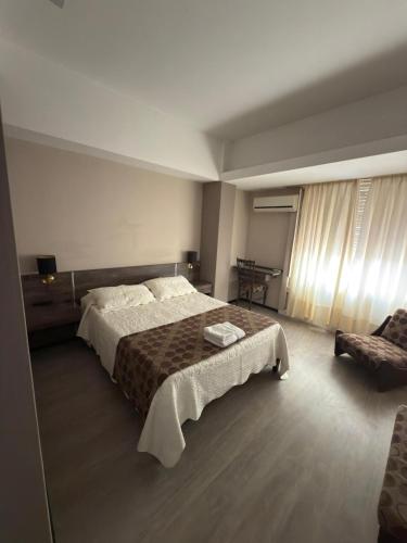 une chambre avec un grand lit et une chaise dans l'établissement Aires del Libertador - Alquiler Temporario en Centro San Francisco, à San Francisco