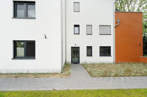 an orange door on the side of a white building at Residenz am Yachthafen Seaside Marina in Neustadt in Holstein