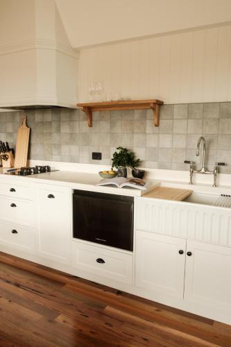 a kitchen with white cabinets and a sink at Skyfarm Retreat in Cradoc