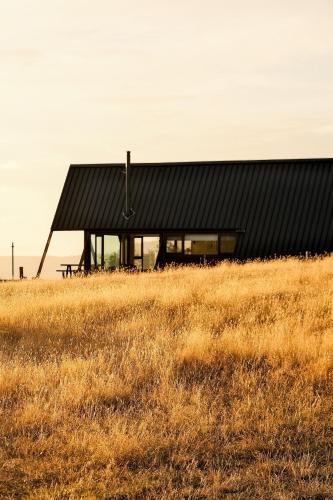 a black building in a field of dry grass at Skyfarm Retreat in Cradoc