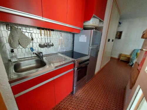 une petite cuisine avec des armoires rouges et un évier dans l'établissement Appartement 2 pièces avec loggia à 150m de la plage, animaux acceptés, garage compris - FR-1-776-111, à Argelès-sur-Mer