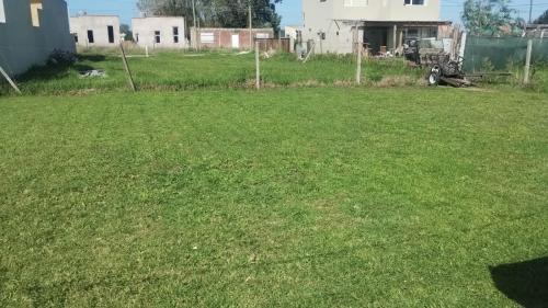 a field of grass with houses in the background at Posada Camet in Camet Norte