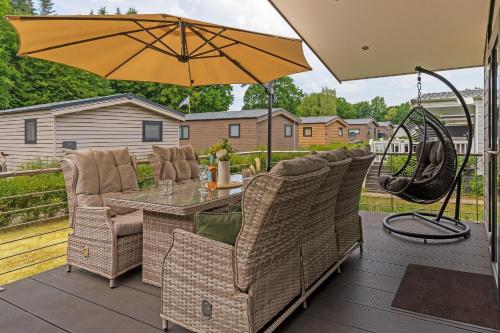 a patio with a table and chairs and an umbrella at Ferienhäuser Lübecker Bucht Ferienhaus Beachcomber in Stubbenberg