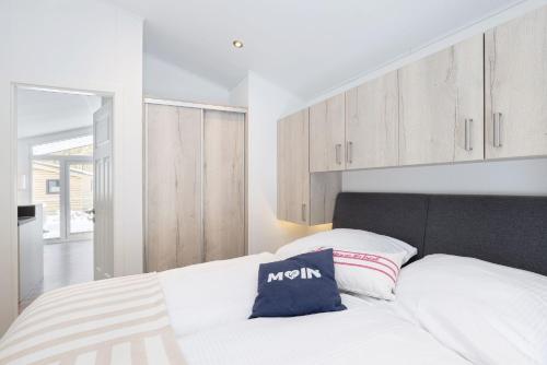 a bedroom with a white bed and wooden cabinets at Ferienhäuser Lübecker Bucht Ferienhaus Beachcomber in Stubbenberg
