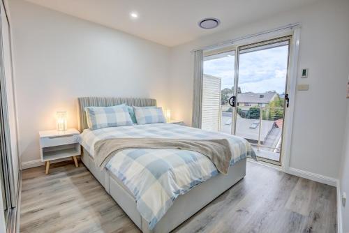 a bedroom with a bed and a large window at Lakeview Family Retreat Canberra Cozy Townhouse in Gungahlin
