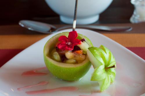 a green apple with a flower on a white plate at Naledi Lodges in Balule Game Reserve