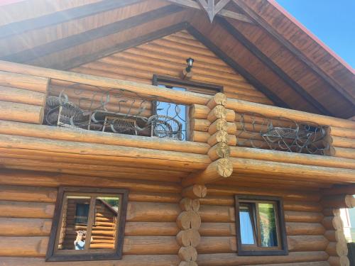 a log cabin with a balcony on top of it at Smerekovyi Dvir in Polyana