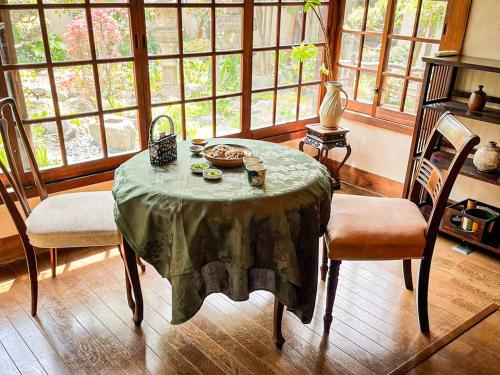 a dining room with a table and chairs and windows at 泉庵-奈良と大阪の結び目 小阪に佇む 和のやすらぎ宿 in Osaka
