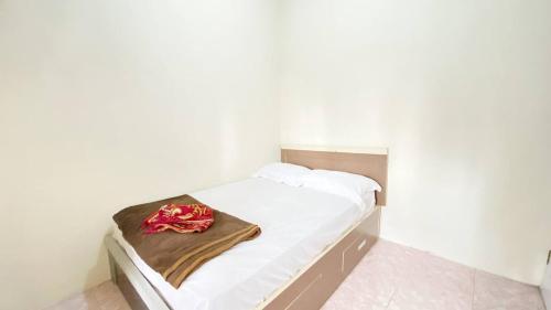 ブキティンギにあるVilla Palacios Syari'ah Bukittinggiの茶色の毛布が掛けられたベッドのある小さな白い部屋