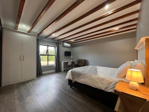 a bedroom with a large bed with a wooden ceiling at Val Mor country house in Paarl