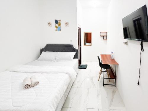 Habitación blanca con 2 camas y escritorio. en Graha Indah Ngagel Surabaya RedPartner, en Surabaya