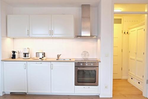 a kitchen with white cabinets and a stove top oven at Dorfring 36 Albatros in Stein