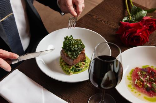 a person cutting a plate of food on a table at The Fullerton Hotel Sydney in Sydney