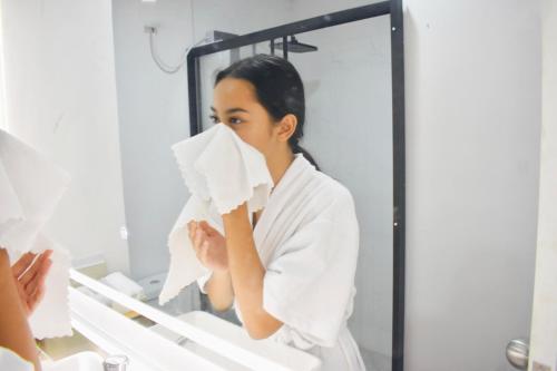 a woman wiping her face in front of a mirror at Bolo Airport Homestay in Lapu Lapu City