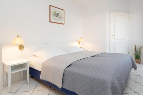 a white bedroom with a bed and a table at Seepferdchen Blomen in Hansaland