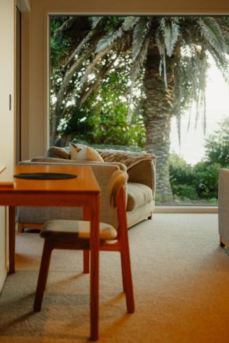 a living room with a couch and a table and a window at Golden Bay Beach Retreat in Parapara 