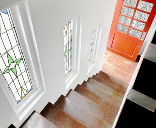 a staircase with a red door and windows at MiraNamin Nest CALACHUCHI Room in Unique Historic Home - Balcony, Rooftop, Garden View, Shared Kitchen, Pet Friendly with a Fee in Manila