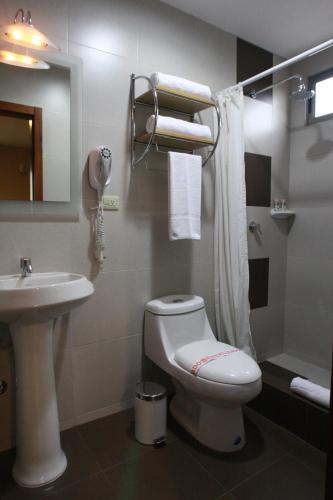 a bathroom with a white toilet and a sink at Hotel Puerto Banana in El Guabo