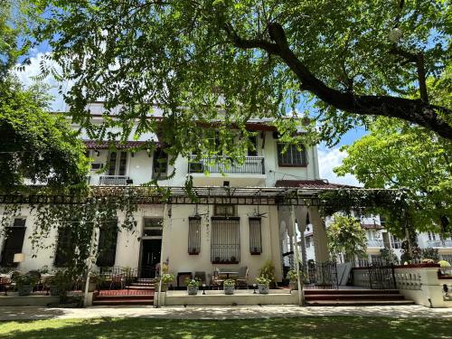 a large white house with a tree in front of it at MiraNamin Nest CALACHUCHI Room in Unique Historic Home - Balcony, Rooftop, Garden View, Shared Kitchen, Pet Friendly with a Fee in Manila
