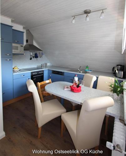 a kitchen with a table and chairs and blue cabinets at Kampenweg 8 Ostseeblick in Puttgarden