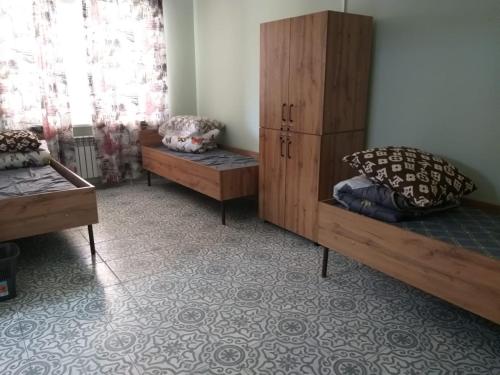 a room with two beds and a cabinet and a window at Hostel House ЖК Ожет in Almaty