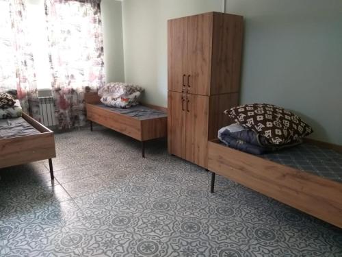 a room with two beds and a cabinet with pillows at Hostel House ЖК Ожет in Almaty