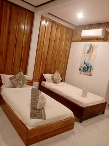two beds in a room with wooden walls at Cam u view Guest House in Nongkhiaw