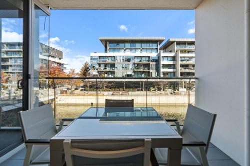 a table and chairs on a balcony with a view of a building at Spacious Lakefront Apartment with Pool Access in Kingston