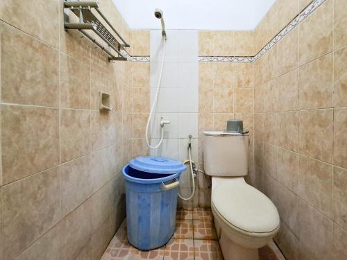 a bathroom with a toilet and a blue trash can at Hotel Djaya RedPartner near Alun Alun Nganjuk in Nganjuk