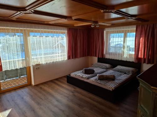 Un dormitorio con una cama y dos ventanas. en Ferienwohnung Grundnergütl, en Leogang