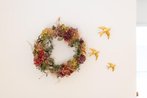 a wreath hanging on a white wall with gold birds at Guest House Waya in Sapporo