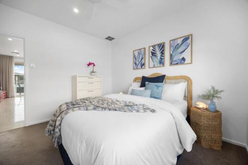 a white bedroom with a large bed with blue pillows at Parea on Cavendish - Luxe Beachside Living in West Beach