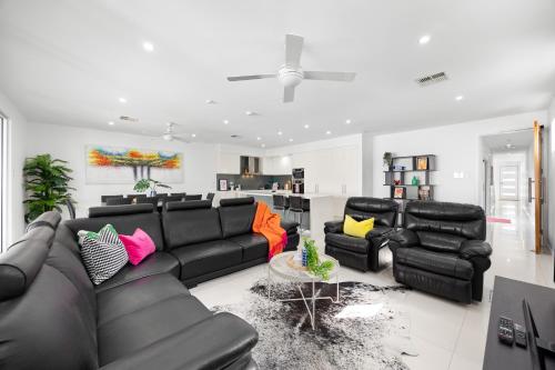 a living room with a black couch and chairs at Parea on Cavendish - Luxe Beachside Living in West Beach