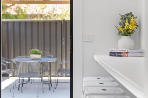 a table and chairs with a vase of flowers on a balcony at Wonderful William - Charming Home close to CBD in Bathurst
