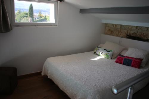 a bedroom with a bed with a window at La Sousta in La Colle-sur-Loup