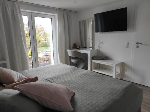 a white bedroom with a bed and a window at Ferienwohnung Traumblick in Bretzfeld