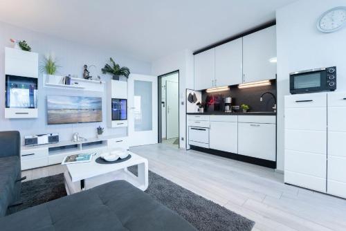 a kitchen with white cabinets and a living room at Mija in Süssau